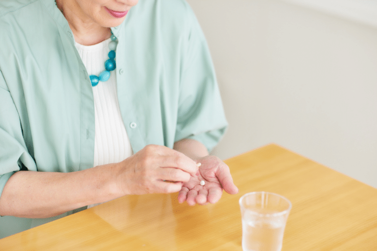 A close-up of a small pill in a woman's hand, with soft lighting and a clean background