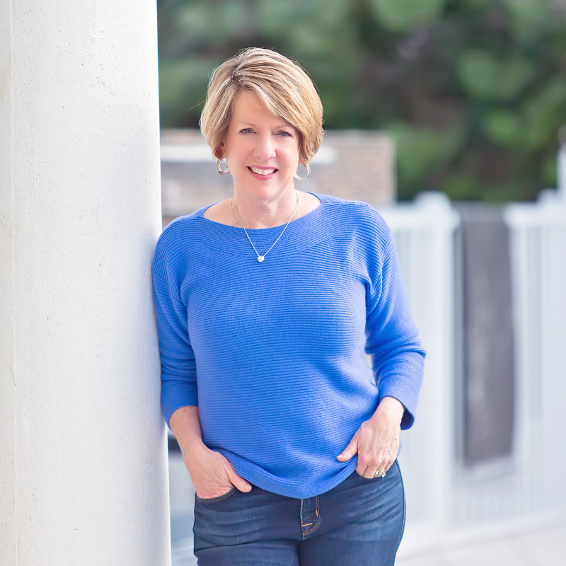 Dr. Anna Garrett, women's hormone health expert, smiling in casual blue sweater outdoors - approachable menopause and perimenopause specialist