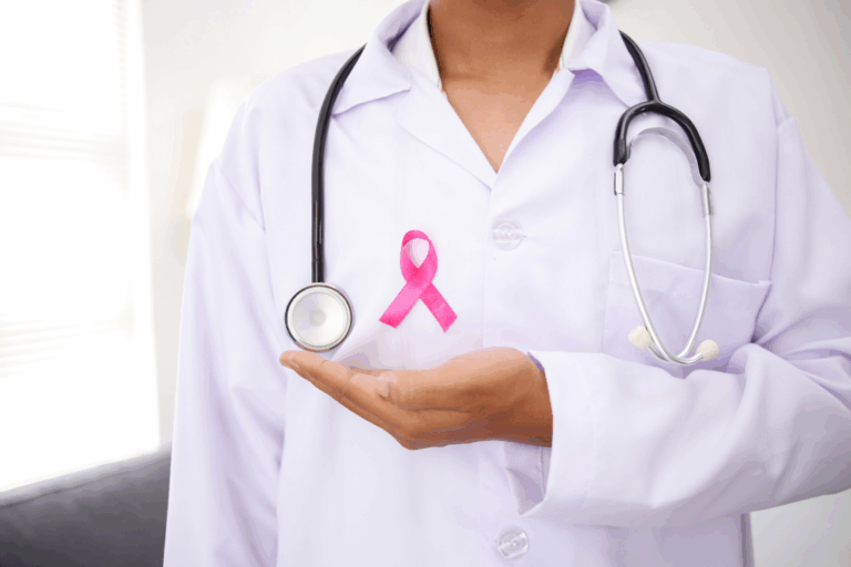 Female doctor wearing white coat with pink breast cancer awareness ribbon and stethoscope