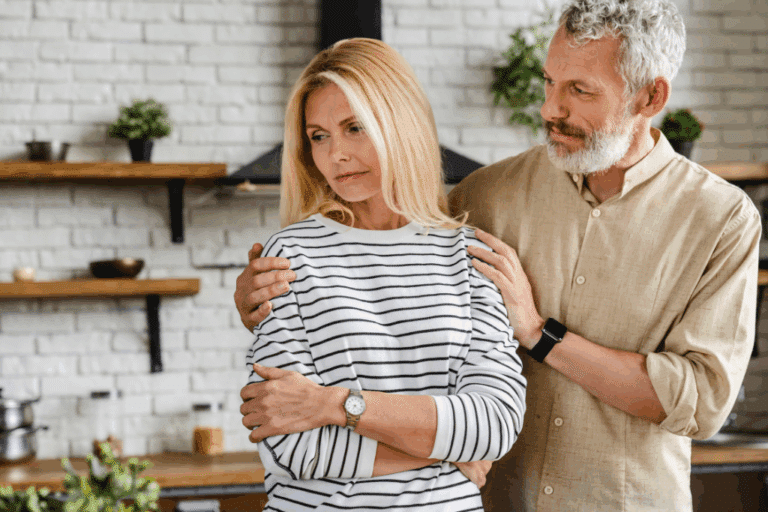 Midlife couple in kitchen discussing intimacy challenges during perimenopause and menopause with woman looking concerned about low libido