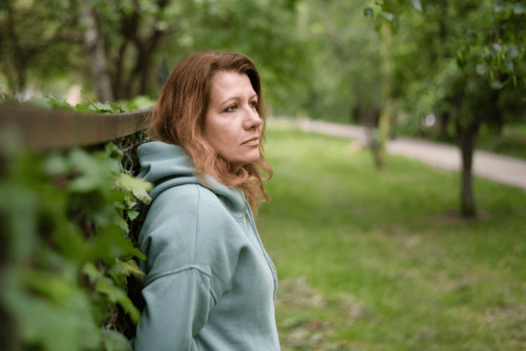 Midlife woman in green hoodie outdoors looking thoughtful representing progesterone myths and hormone balance concerns in perimenopause and menopause