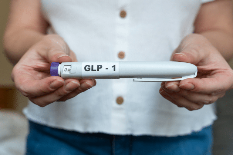 Woman holding a GLP-1 injection pen, illustrating GLP-1 medication options for PMOS and PCOS insulin resistance treatment