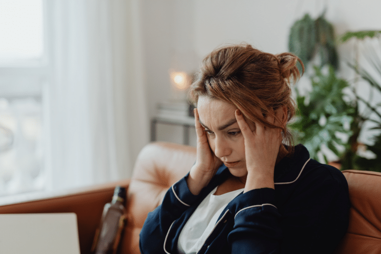 Midlife woman holding her head in distress, representing perimenopause anxiety and hormone imbalance symptoms