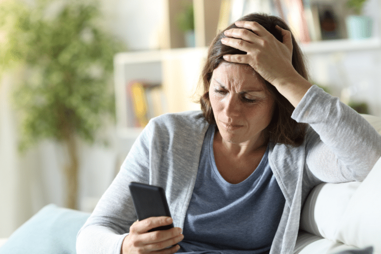 Confused midlife woman researching qualified menopause help on her phone