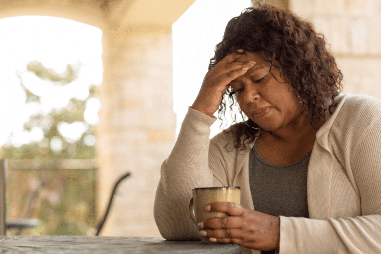 Midlife woman rubbing her forehead in fatigue, showing signs of perimenopause symptoms like brain fog and exhaustion